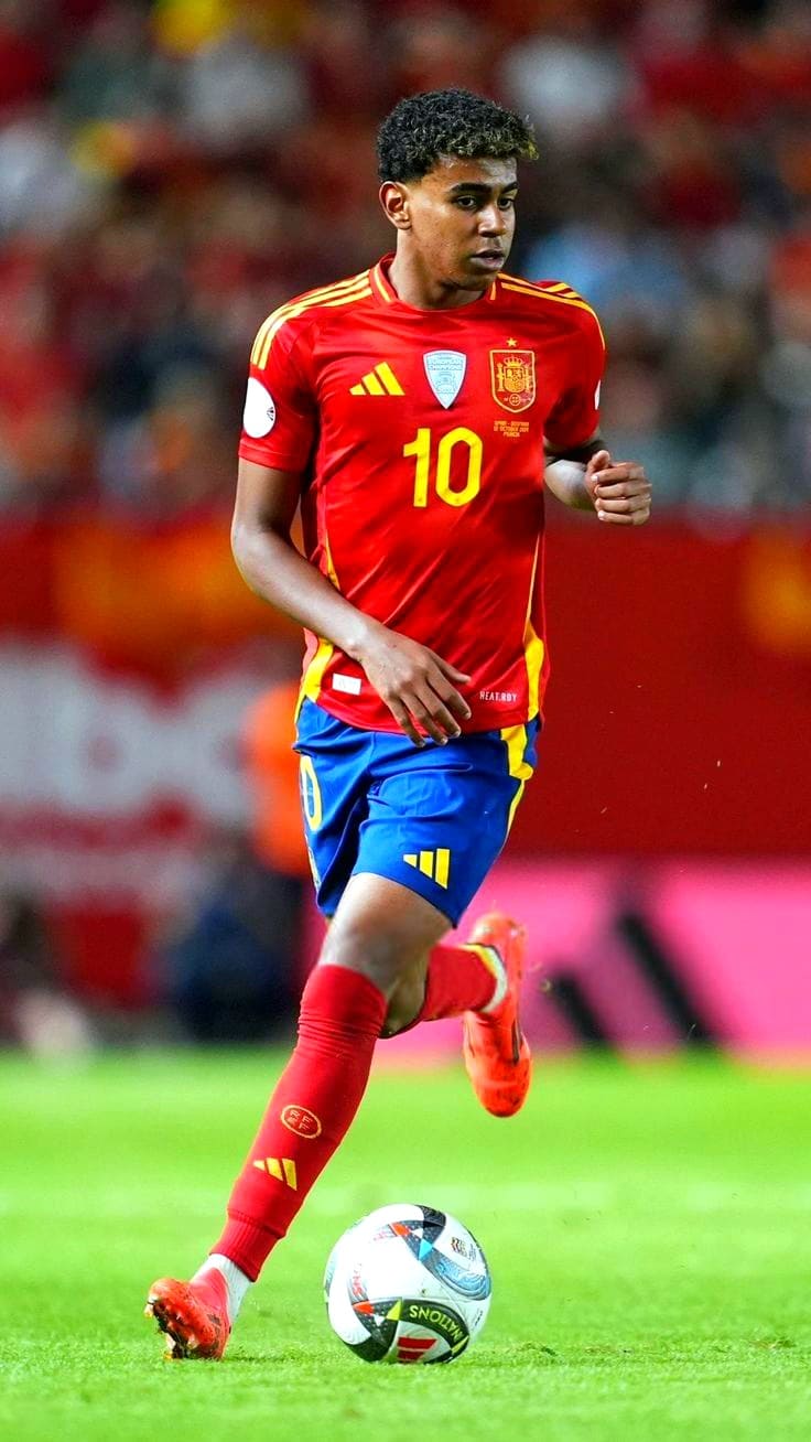Croatia IPTV A soccer player in a red and yellow Spain national team uniform, numbered 10, is dribbling a ball on the field during a match. The background shows blurred spectators, as the action unfolds live for viewers watching via Croatia IPTV.
