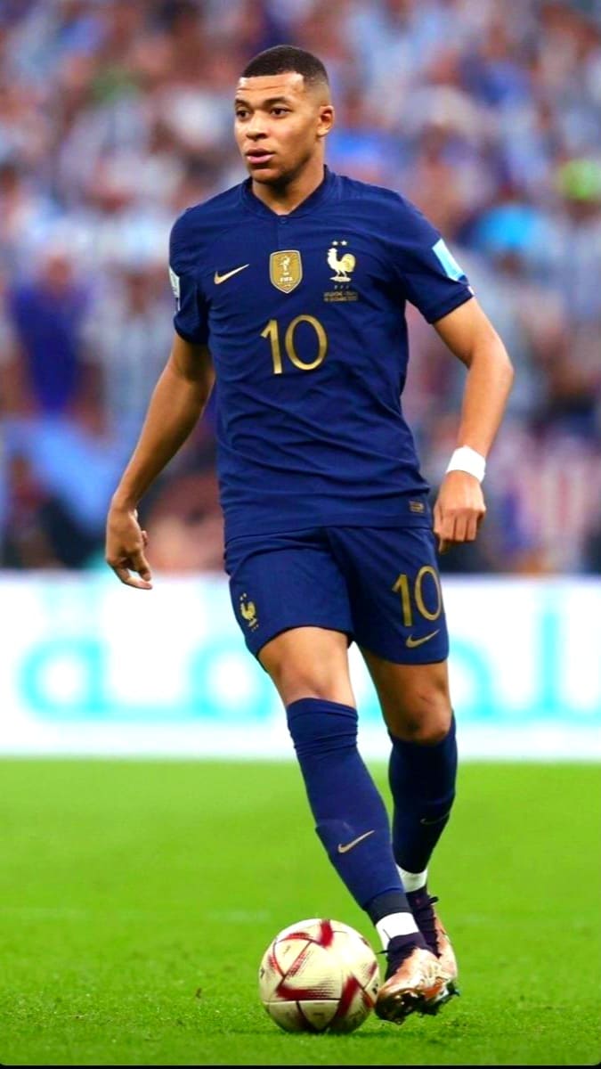 A male soccer player in a blue France national team jersey with number 10 controls a ball during a match on a green field, with a blurred crowd in the background—perfect for fans catching the action live on Croatia IPTV.