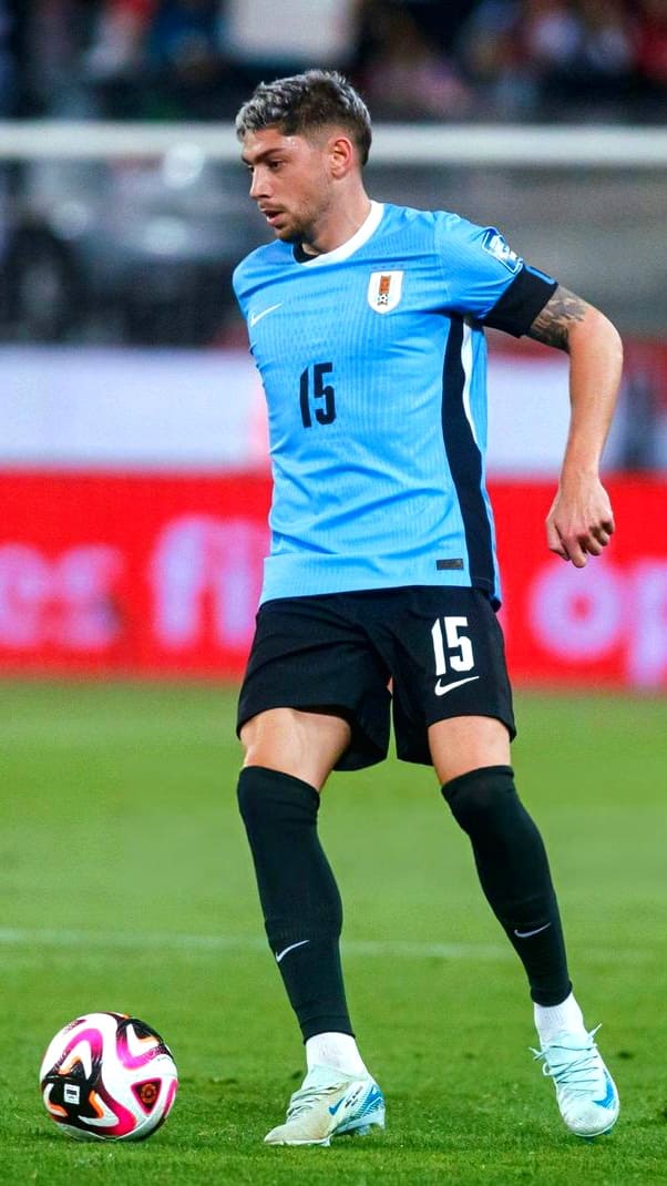 A soccer player wearing a light blue jersey with the number 15 is dribbling a ball on a field during a match, as the action is broadcast live on Croatia IPTV.