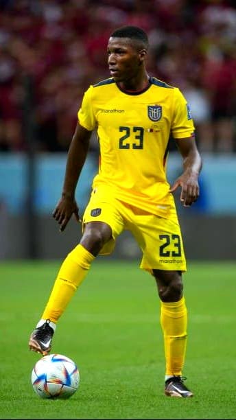 A soccer player in a yellow Ecuador uniform with the number 23 controls the ball on the field during a match, as fans watch from the blurred crowd—perfect action to catch live on Croatia IPTV.