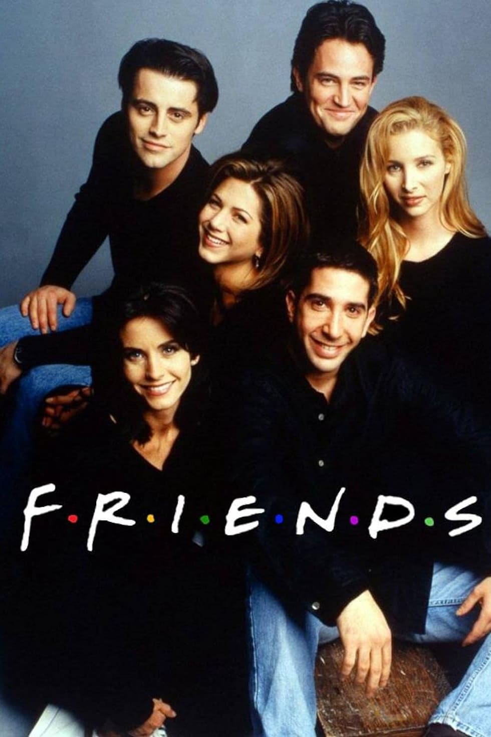 Six people sit and smile together against a gray background, wearing dark clothing. The word FRIENDS appears in white text with colored dots between each letter at the bottom of the image, evoking the familiar feel of watching classic sitcoms on platforms like Croatia IPTV.